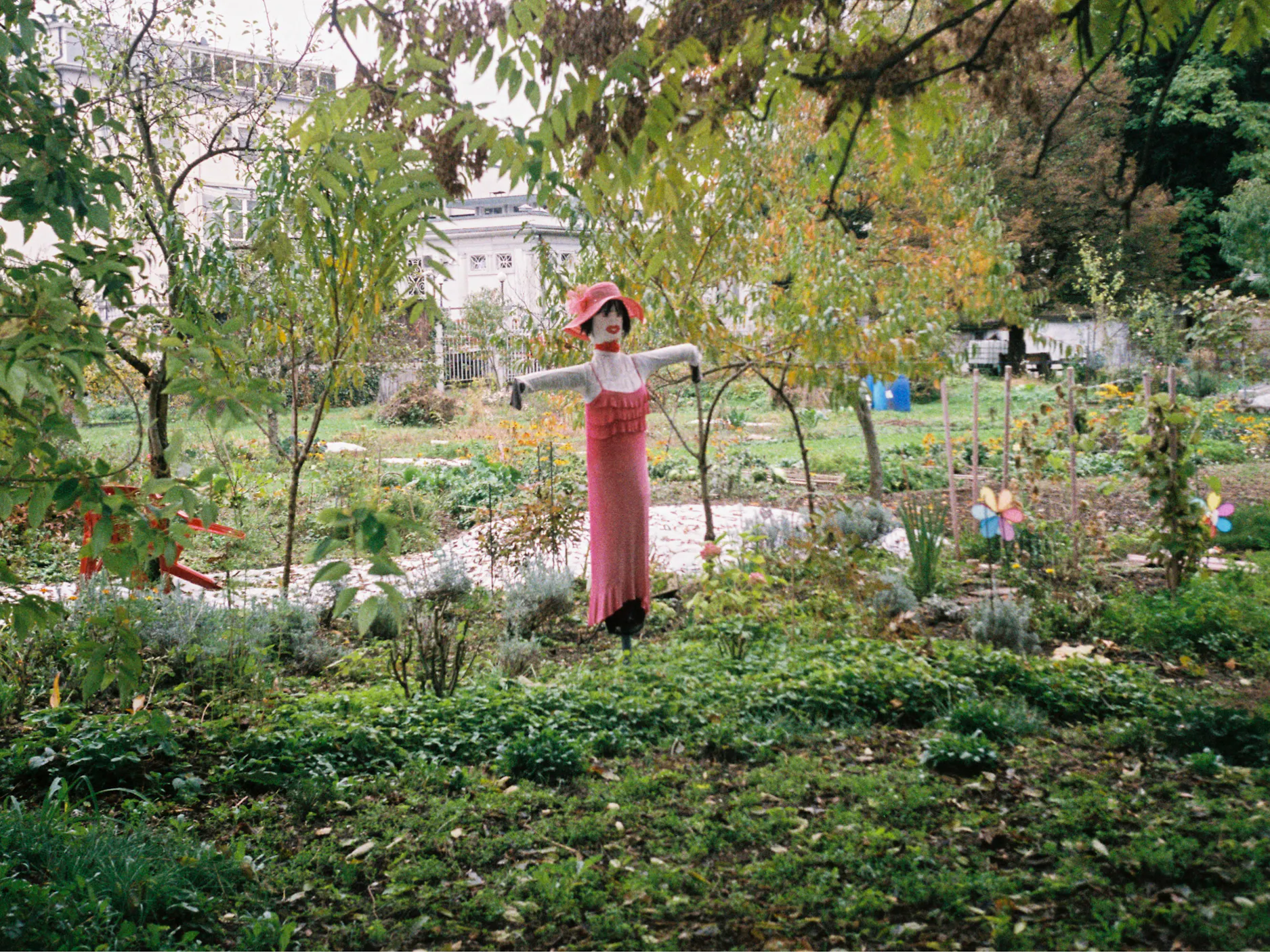 Strašilo za ptiče na vrtu oblečeno v ženska oblačila v rdeči barvi.